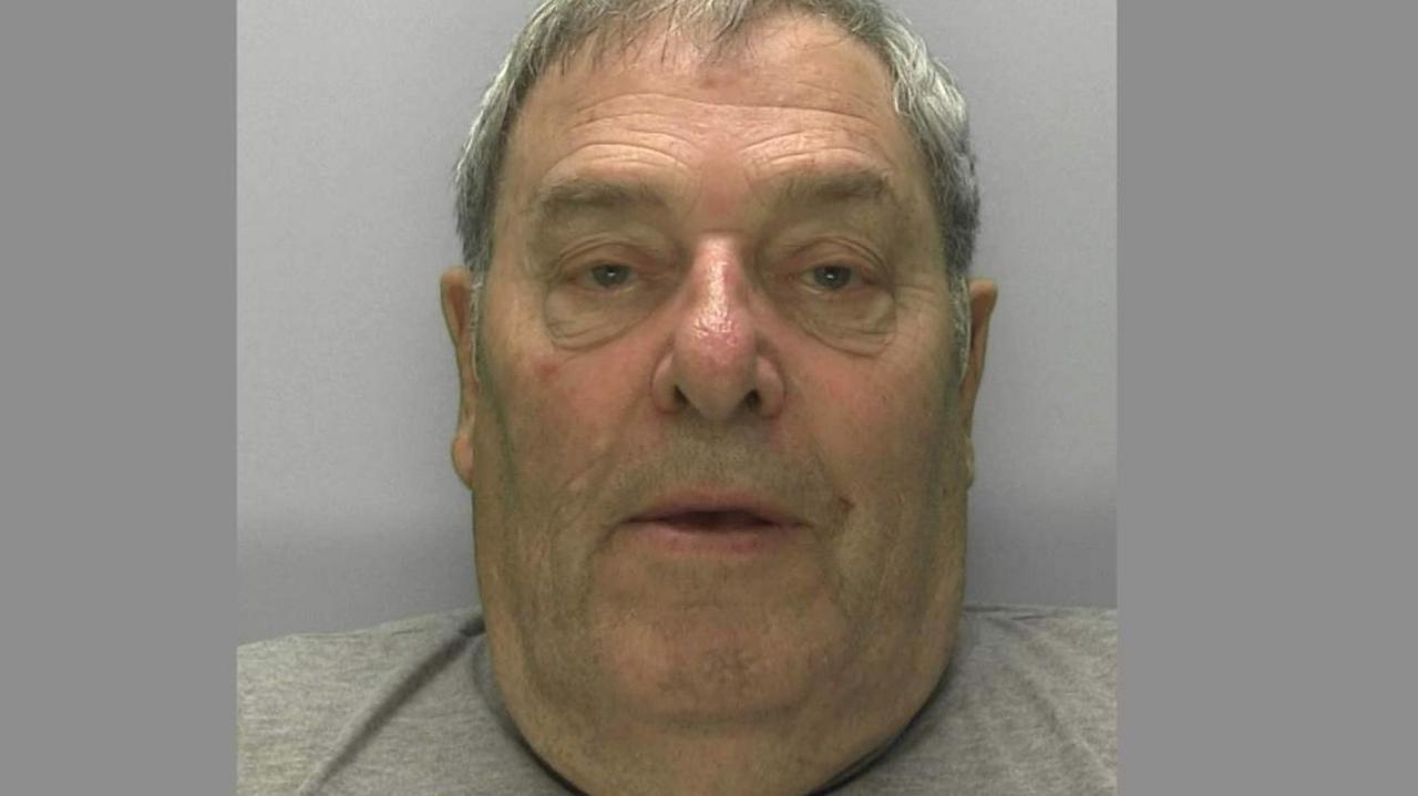 A mugshot of Charles Graham, who has grey hair and is wearing a light grey jumper.