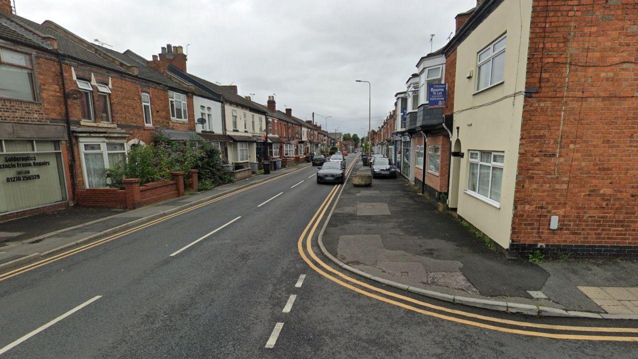 A Google street view image of a road with terraced properties on either side. Cars can be seen parked at the side, on the pavement and driving down the road.