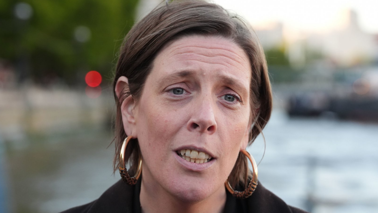 Headshot of Home Office Minister Jess Phillips. She has her short, light brown hair tucked behind her ears. She wears a thick black, jacket and very large gold hoop earrings.