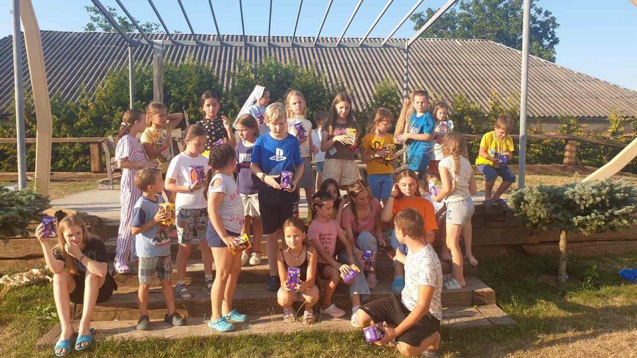 Twenty four children in summer clothing in a playground in Ukraine with chocolate easter eggs