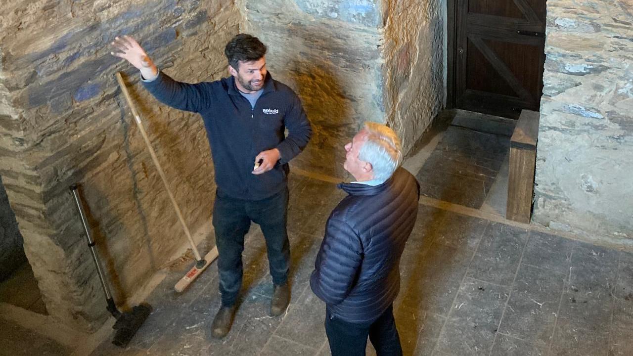 Two men, Ryan Byrne and Neil Doherty, are standing inside the fort. 
One is gesturing upwards with his hand while the other follows his direction. 
Both men are wearing navy coats and jackets.