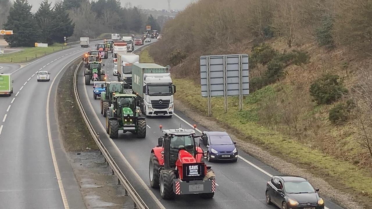 Tractors are pictured heading down one of the lanes of the A14. Other vehicles drive past them in the parallel lane.