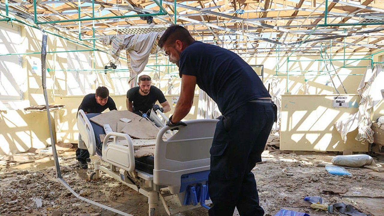 Men roll damaged hospital bed through wreckage