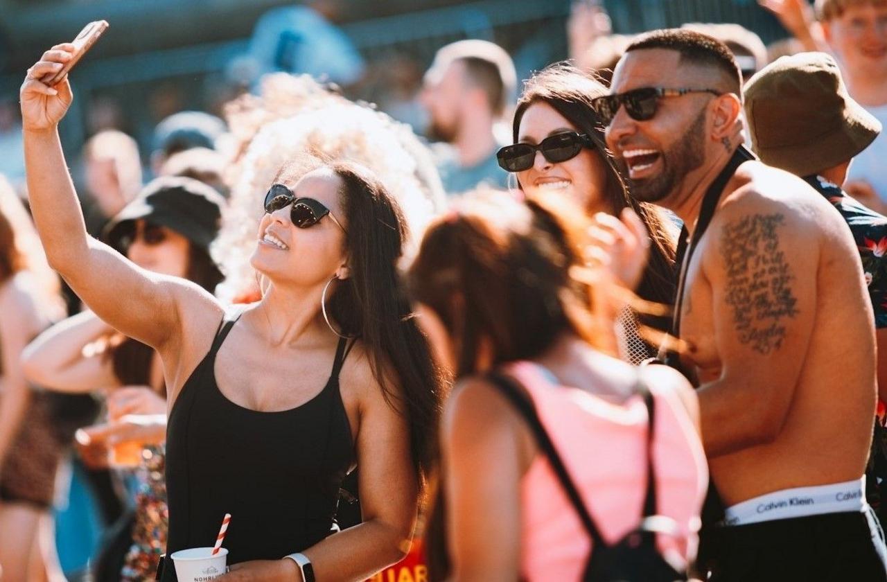 A group of young people smile as they pose for a selfie at Bristol Sounds 2024. One of the young men has his top off, showing it is a hot day