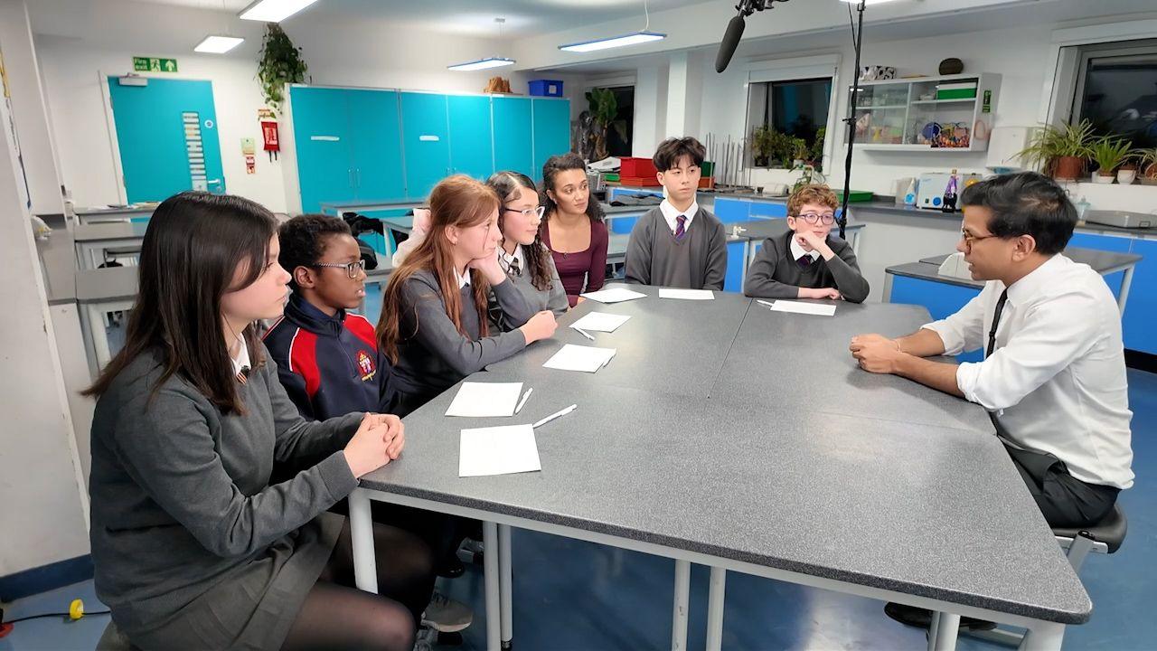 The government's Minister for AI and Online Safety, Kanishka Narayan spaks to children across a table in a school science lab. 