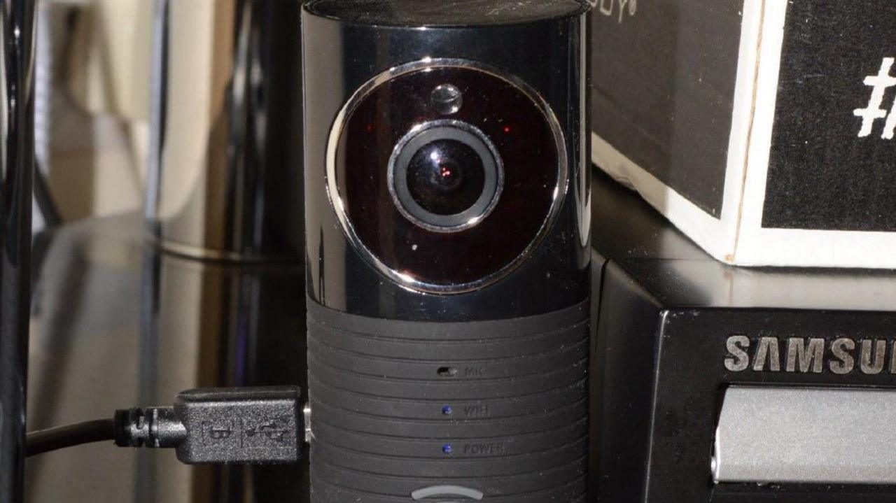 A small black camera on a desk with a USB cable plugged into it.