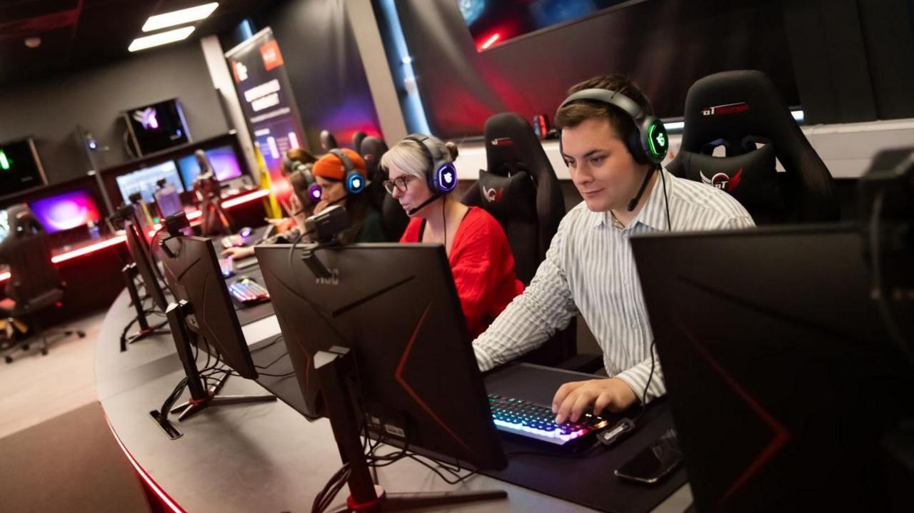 People sat at a bank of desks in the new e-sports lab