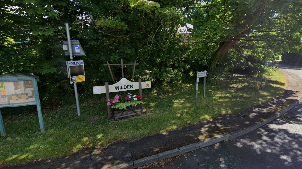 The centre of of Wilden where the village notice board is visible and a sign with the name of the village.