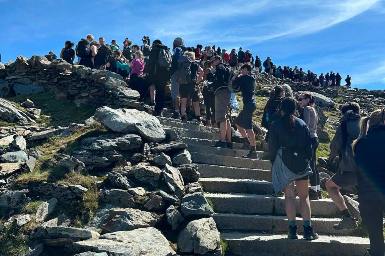 People queue on stone steps leading up the mountain.