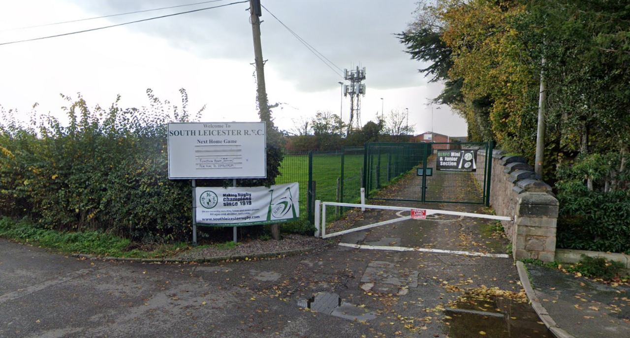 A gate road leading past a field to a rugby club