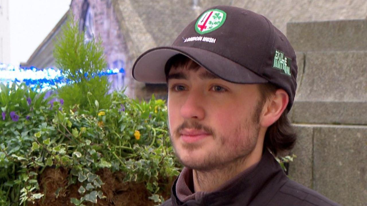 Young man in black cap and jacket sitting on a bench in St Peter Port