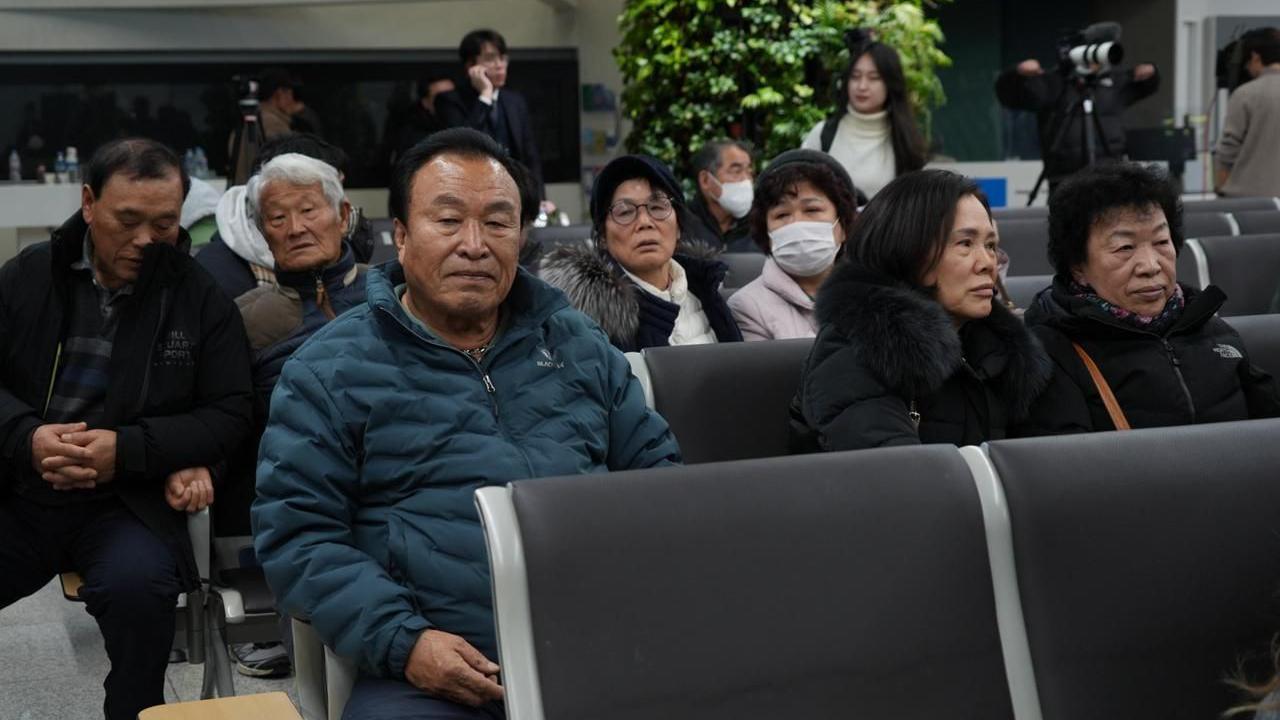 Mr Maeng with a sombre expression sits among other grieving family members of the crash victims at Muan Airport.