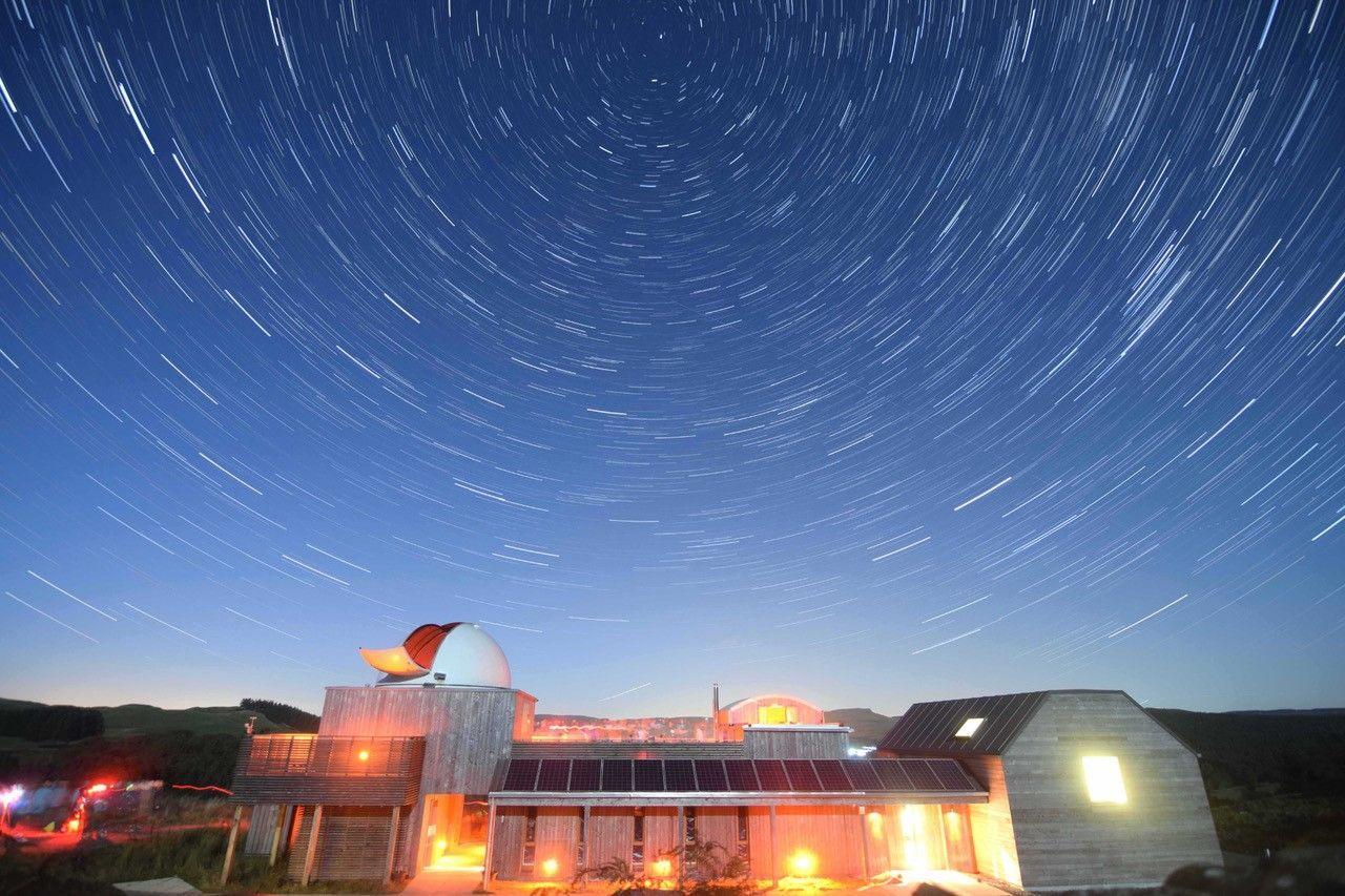 A brightly lit observatory building beneath a swirling starry sky