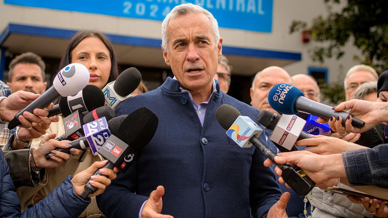 Presidential candidate Calin Georgescu speaks into lots of press microphonesand looks away from camera outside in Bucharest on 1 October, after he announced he's running as an independent candidate for president.