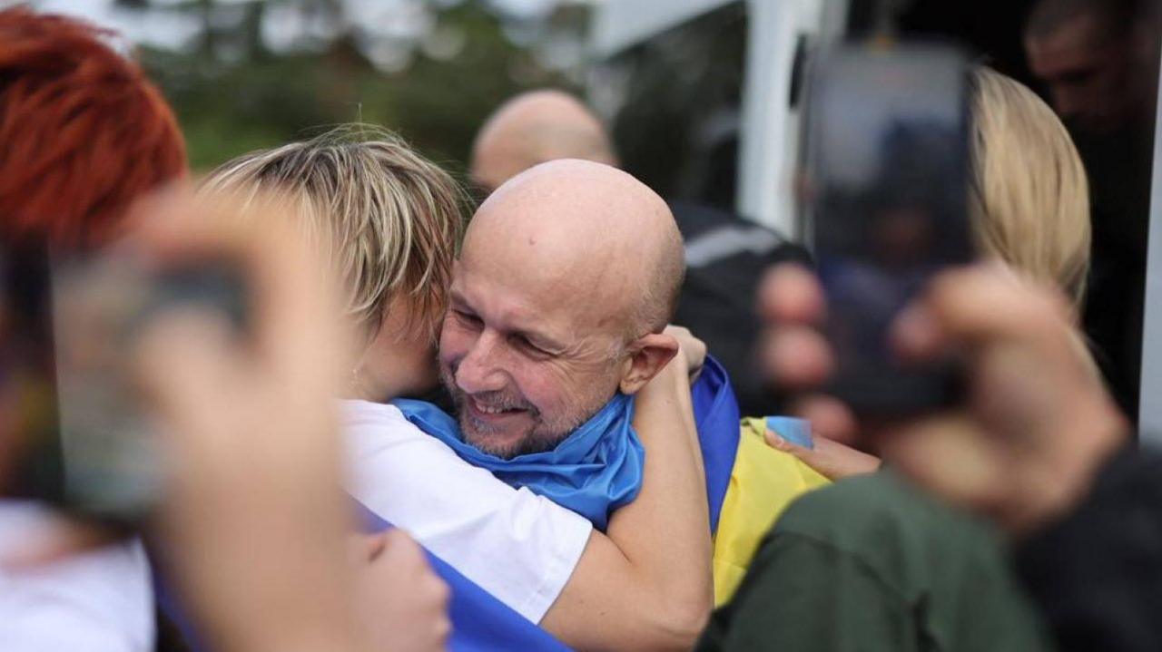 A Ukrainian man held in Russia for three and a half years grins and hugs a woman on his release in August 2025