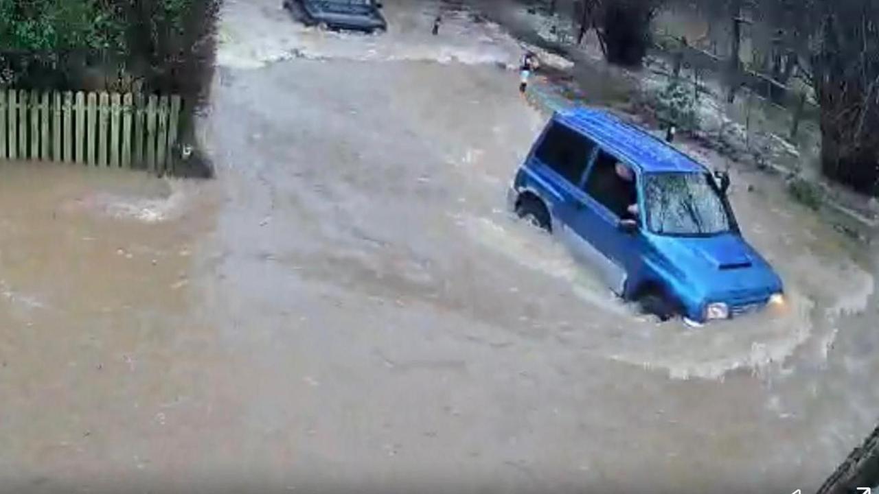 A blue car is stuck in floods in a street in Hellingly with water as high as its wheels