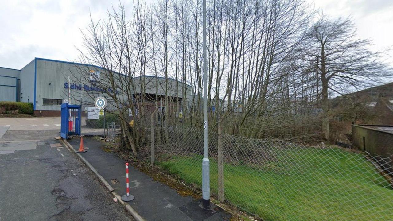 Sidhill Business Park in Holmfield. It shows a large industrial-type building  with fencing and trees bordering the site. 