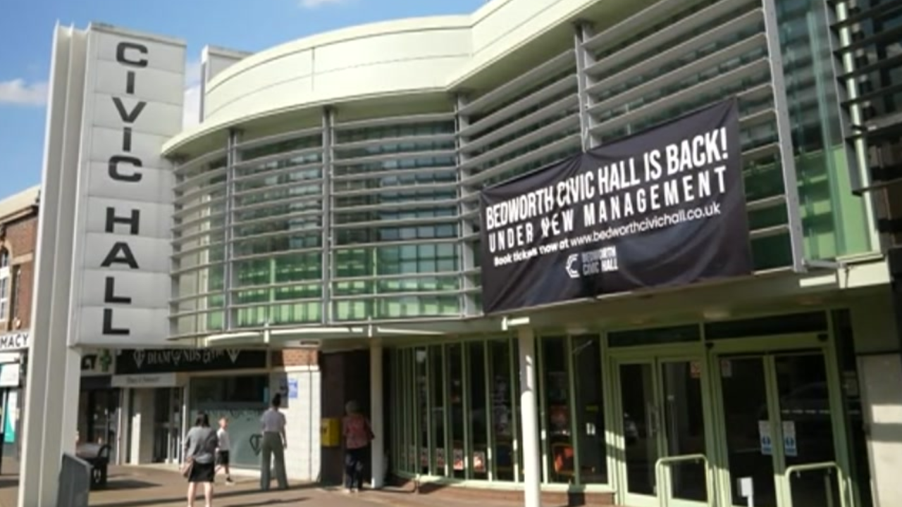 A glass fronted building with a banner saying Bedworth Civic Hall is back