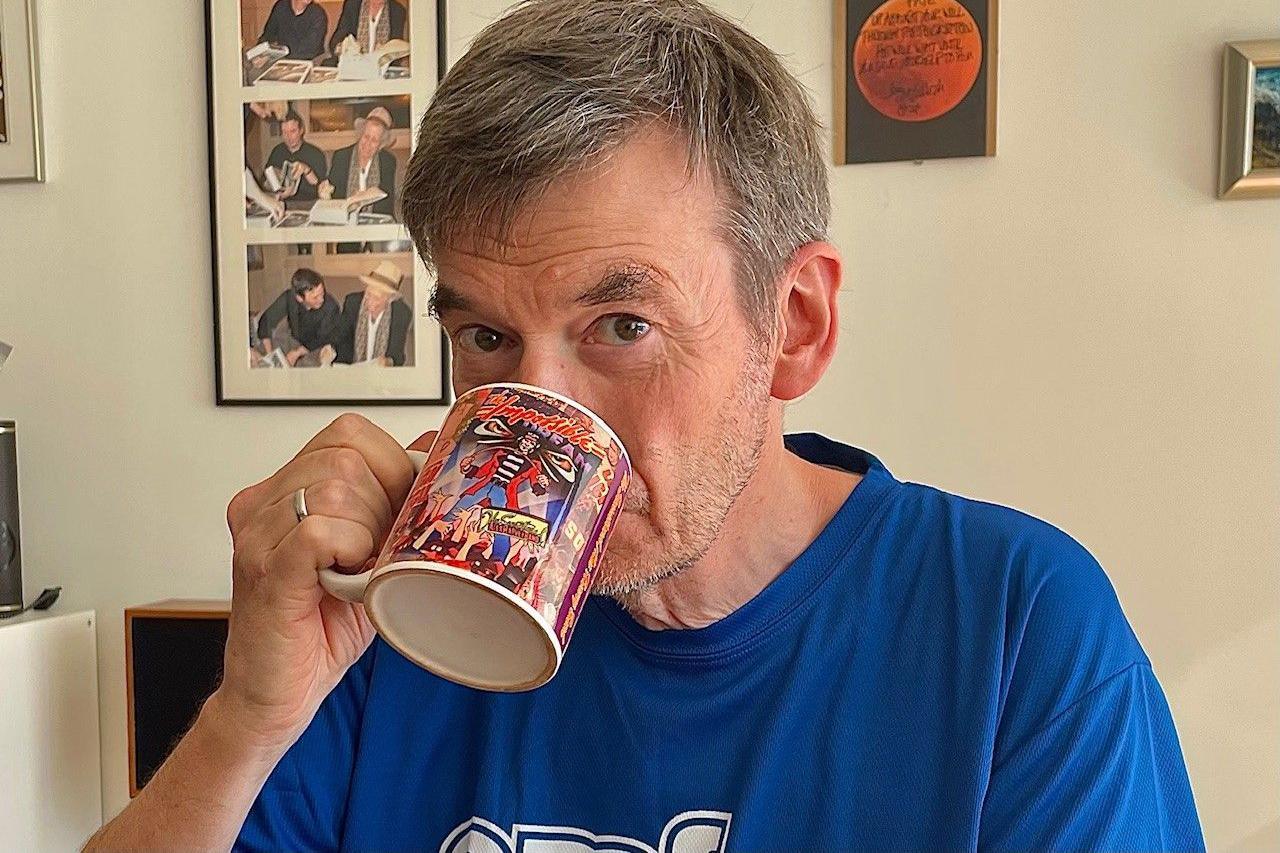 Ian Rankin drinking a cup of tea while looking at the camera 