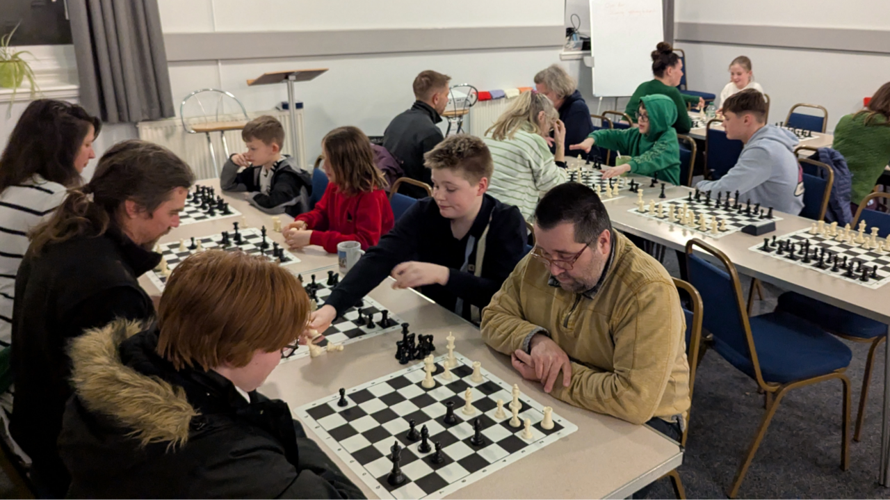 Llun yn dangos ystafell llawn pobl yn chwarae gwyddbwyll.