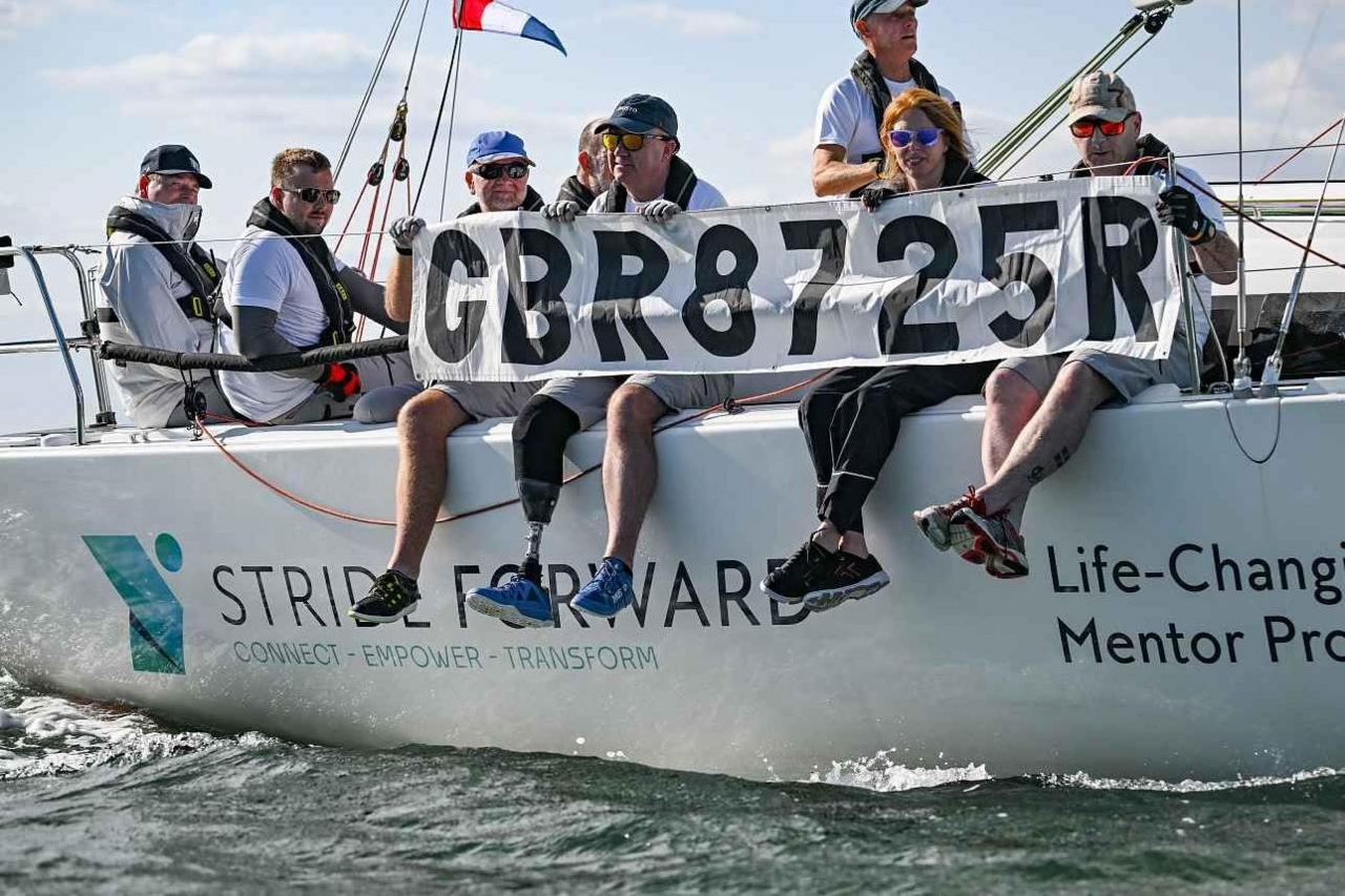 A group of people sitting along the edge of STRIDE FORWARD at Cowes Week