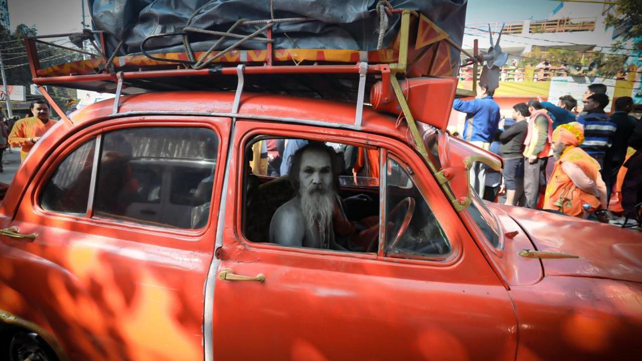 Another holy man arriving in his decorated vintage red car