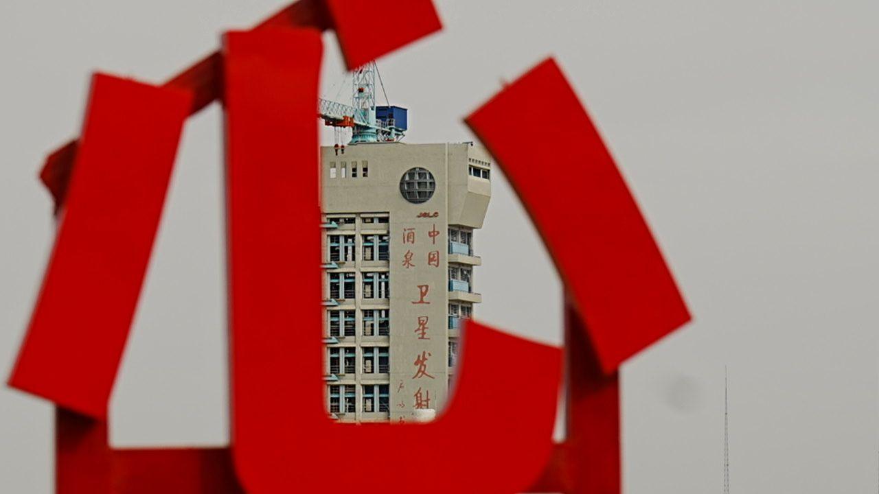 A building next to the launch pad, which has the words - China, Jiuquan, Satellite Launch Centre - in Mandarin