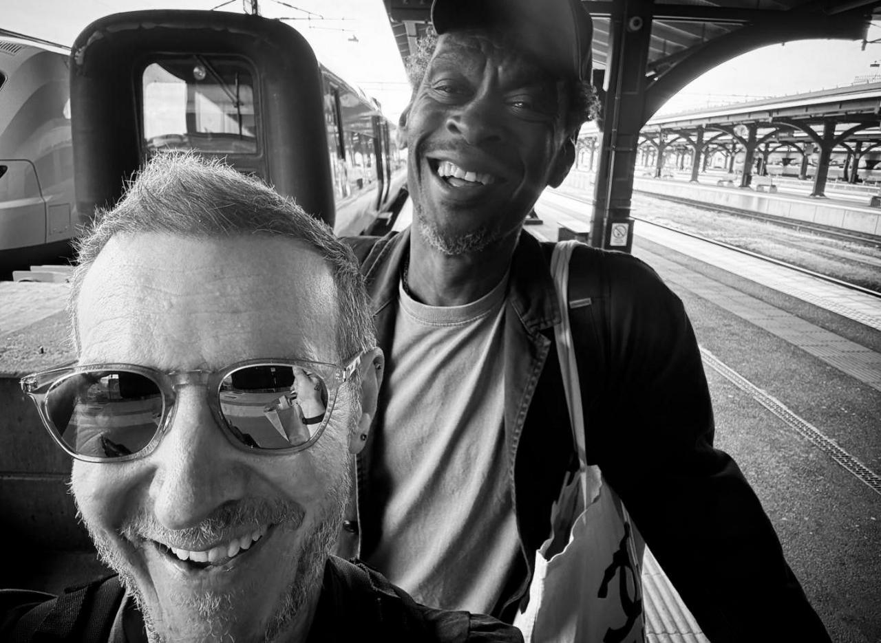 Massive Attack's two band members smiling in a selfie at a train station