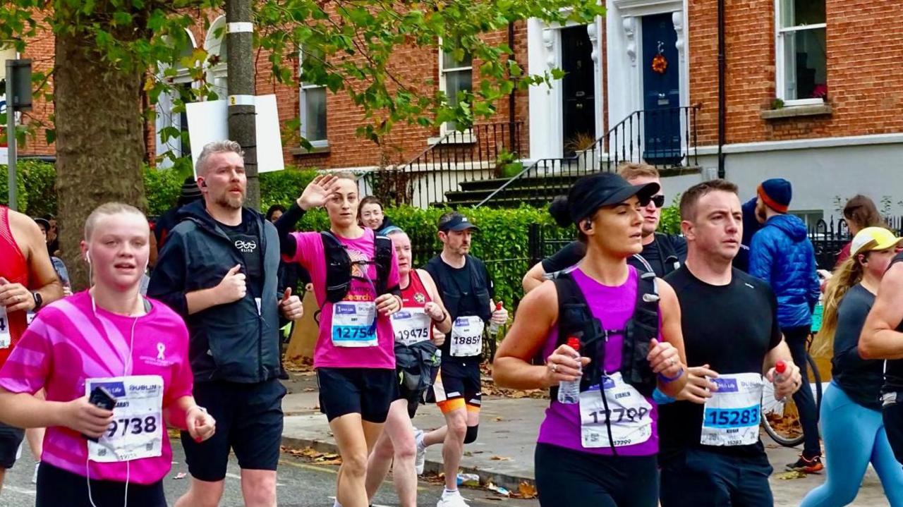 Amy Carr in a pink vest running in the Dublin marathon, surrounded by other runners