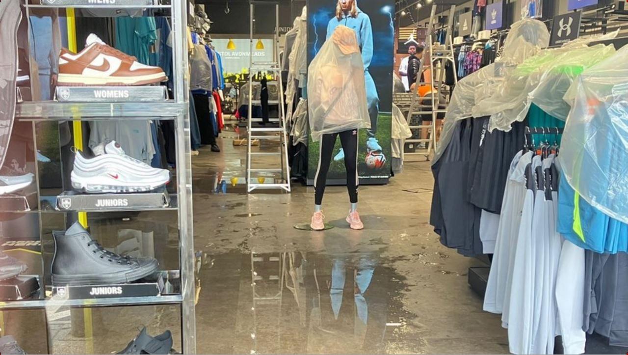 Flooded shop with damaged goods and white plastic bags covering the mannequins