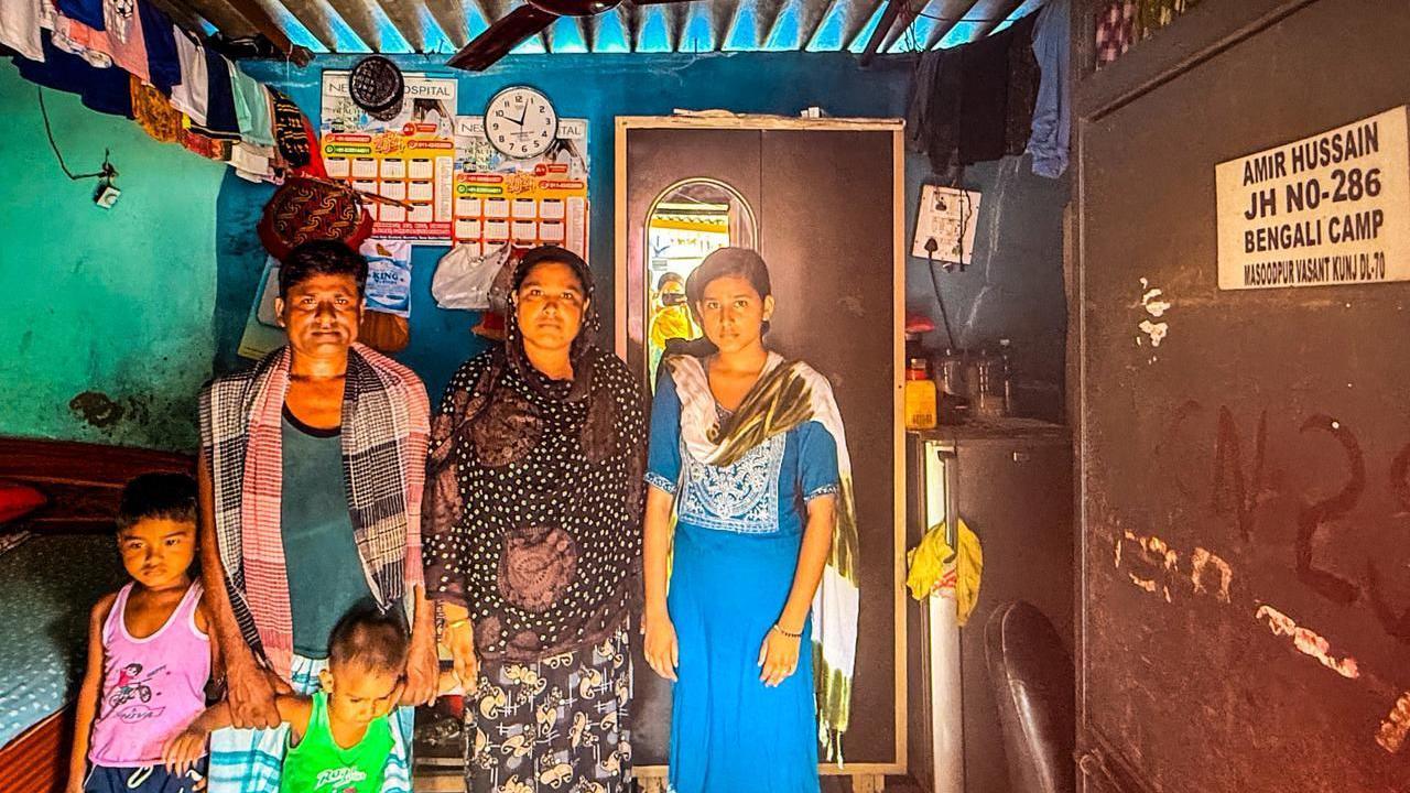 A Bengali-Muslim family - comprising a husband and wife along with their three children - pose inside their home in a slum in Delhi 