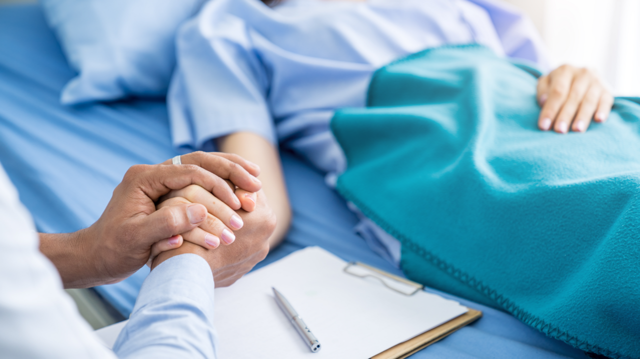 A woman holding a patient's hand