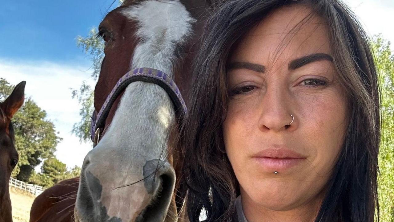 Ms Creasy takes a selfie while standing next to a horse. Ms Creasy has long dark hair and has a nose ring. The horse is a bay colour with a white section stretches from its forehead to its nose.