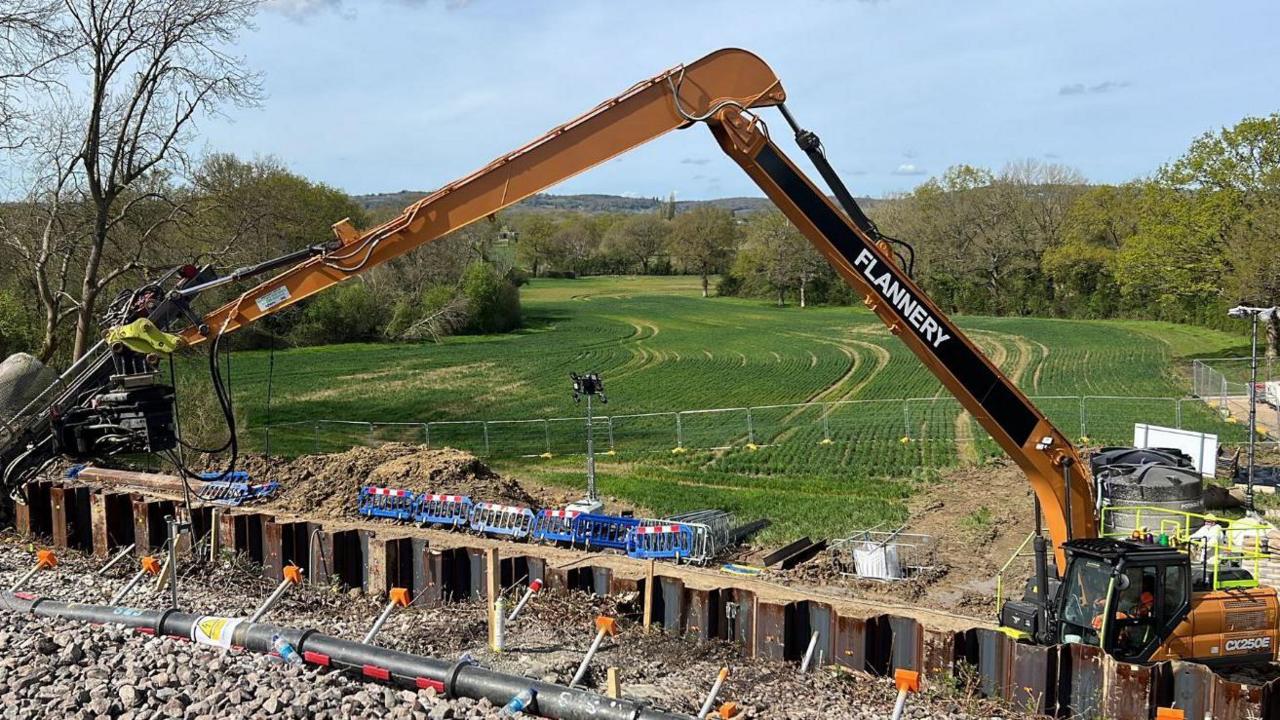 A large crane type construction vehicle is pictured beside the affected section of railway track