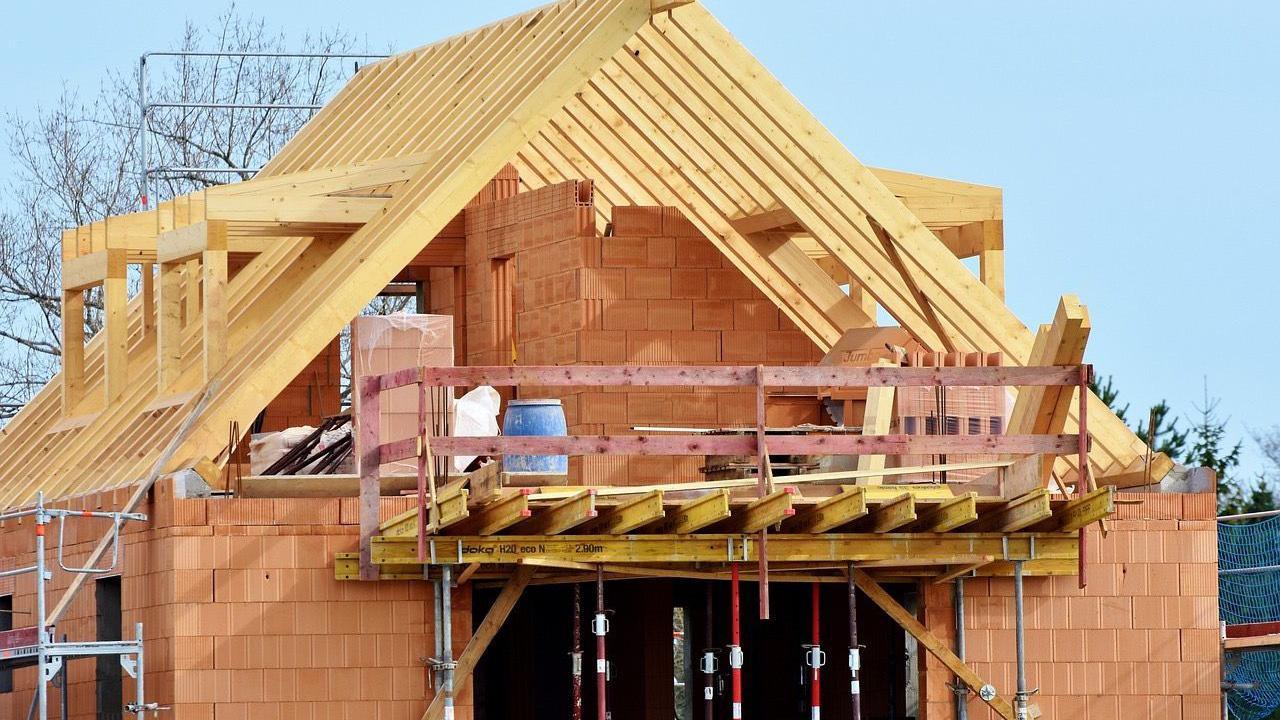 A home is being built with scaffolding and a wooden roof.
