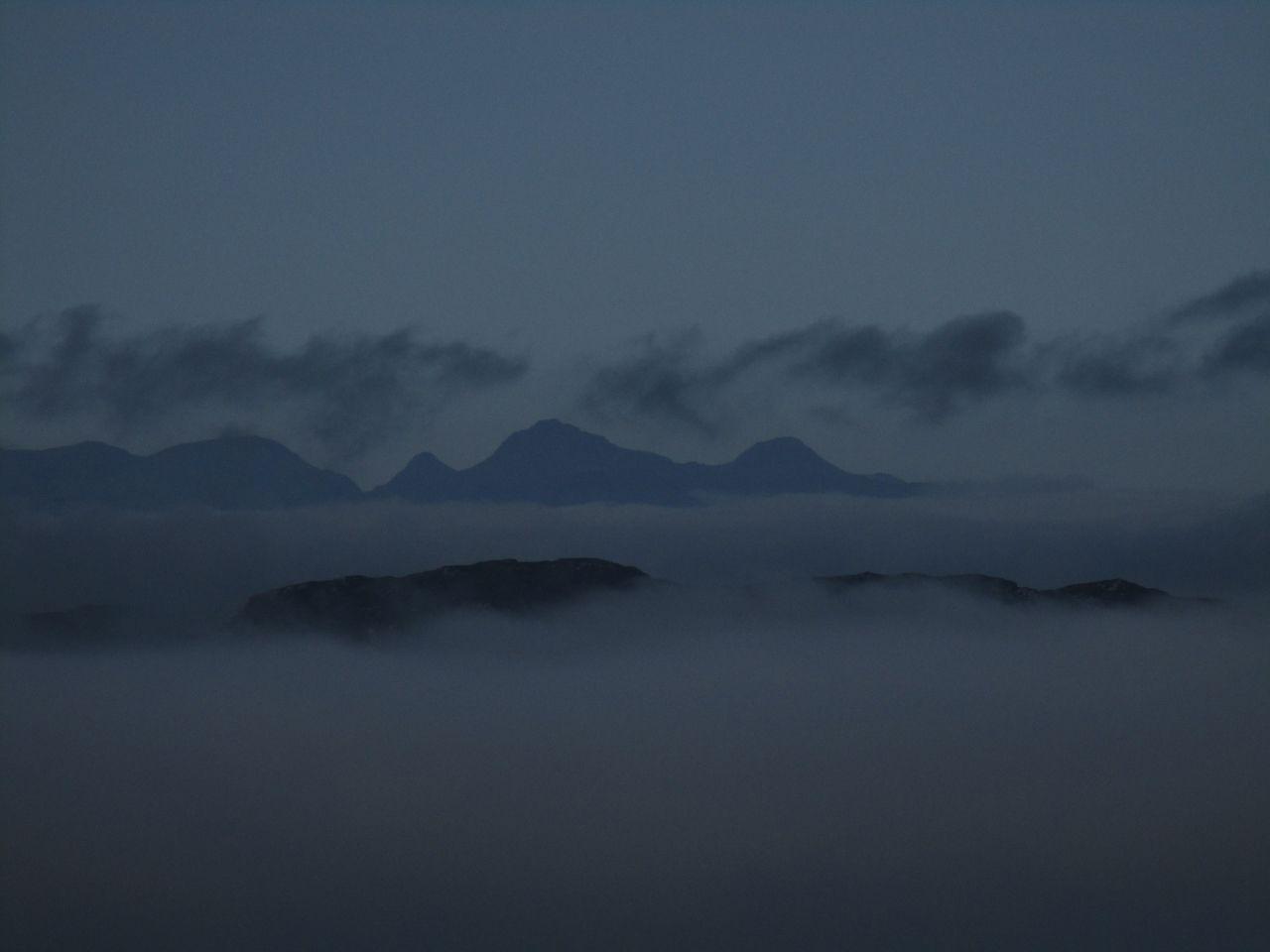 Mountains with clouds in the foreground and background.