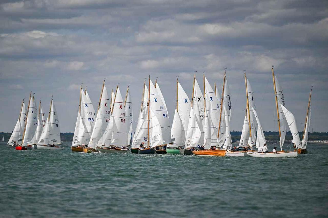 A large group of XL and XOD class sailing boats on the water, including ATHENA, BEATRIX, FOXGLOVE, LARA, MAGIC DRAGON, MIX, SWALLOW and TURTLE.