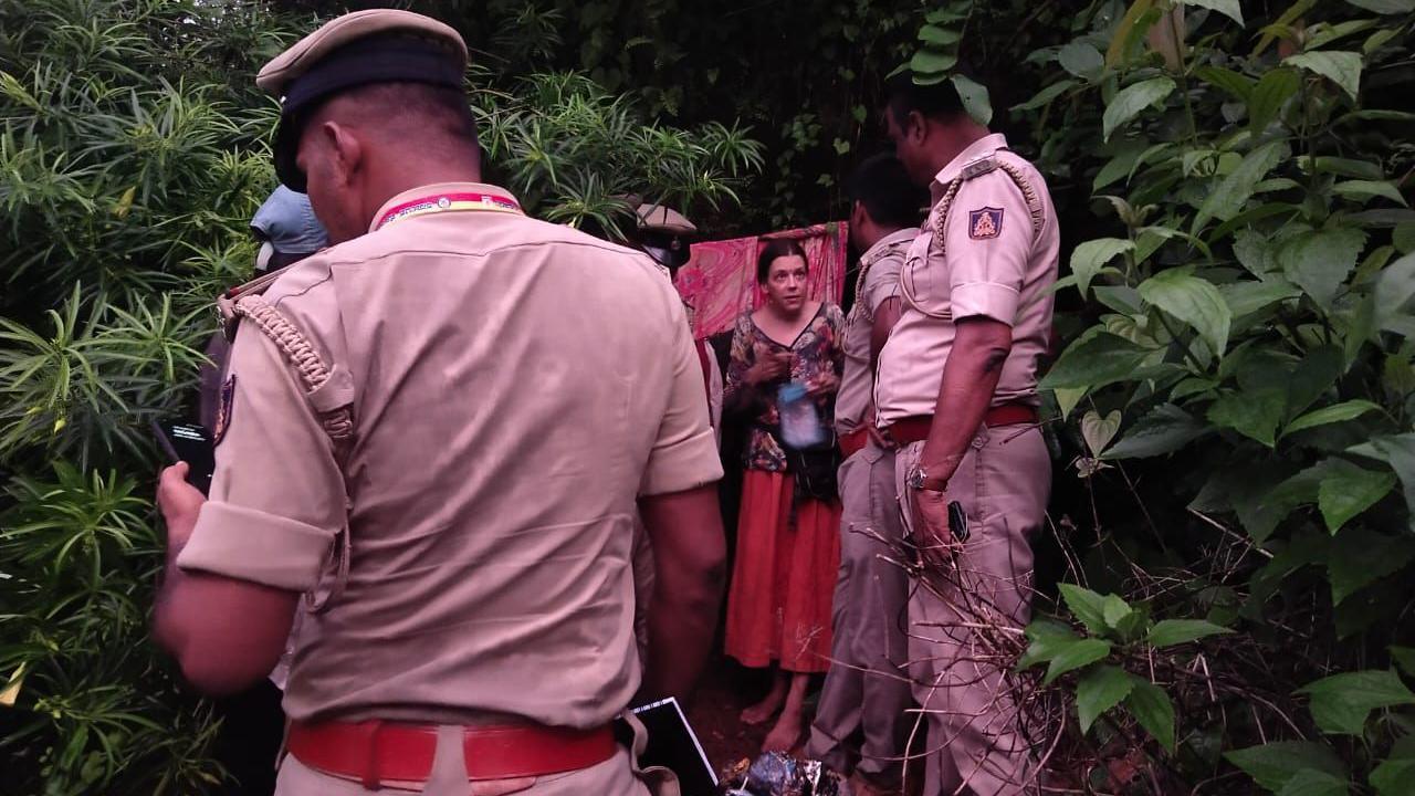 Policemen talking to the Russian woman who stands outside her cave dwelling