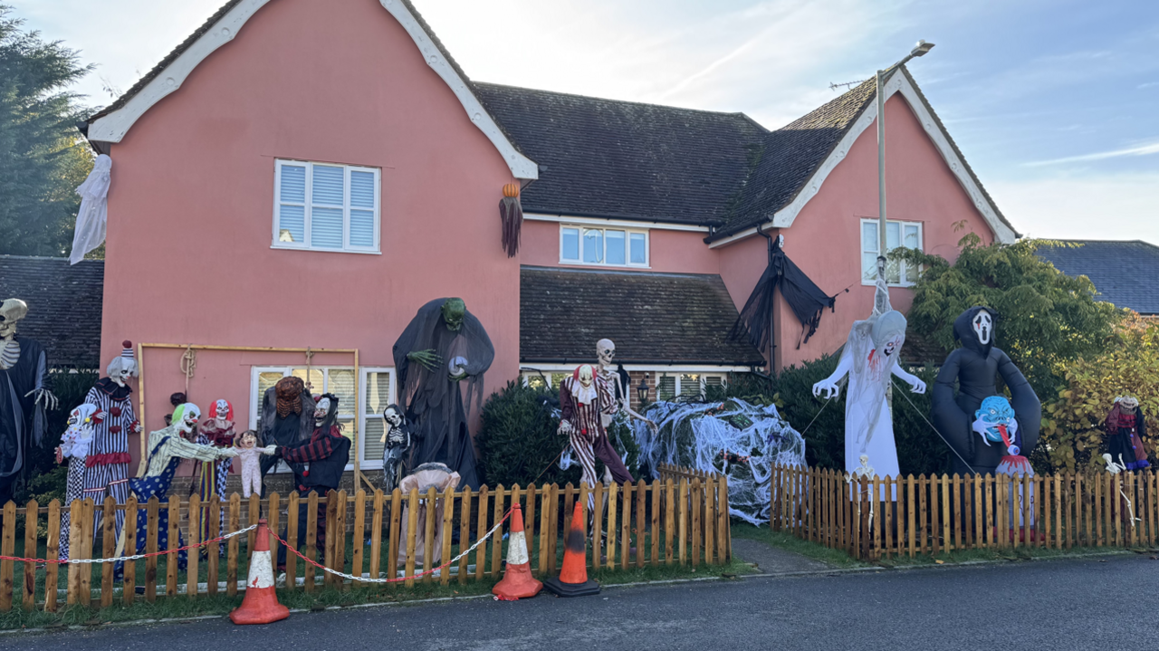 A wide shot showing the entire Halloween display outside Mr Wright's home. Clowns, skeletons, towering figures, witches and more are in shot.