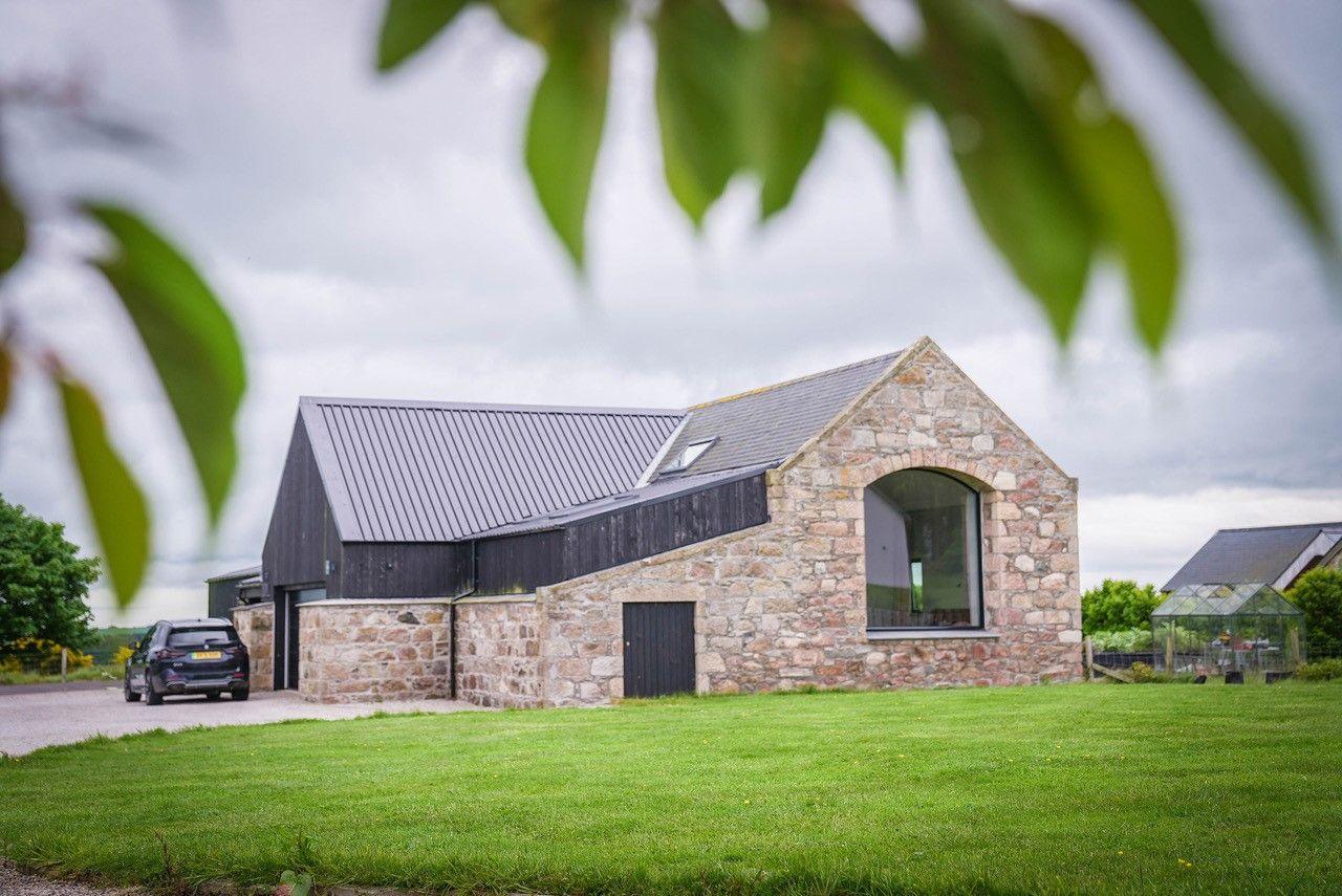 The opposite end of the house is in a blonde stone with another large window, this one with an arched top.