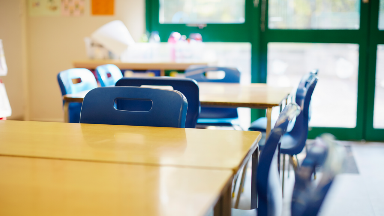 A general view of a classroom with wooden desks and blue chairs