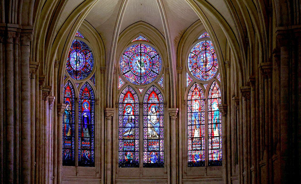 Intricate stained glass windows in many colours are seen doming the roof and wall structure of the cathedral, as taken from inside.