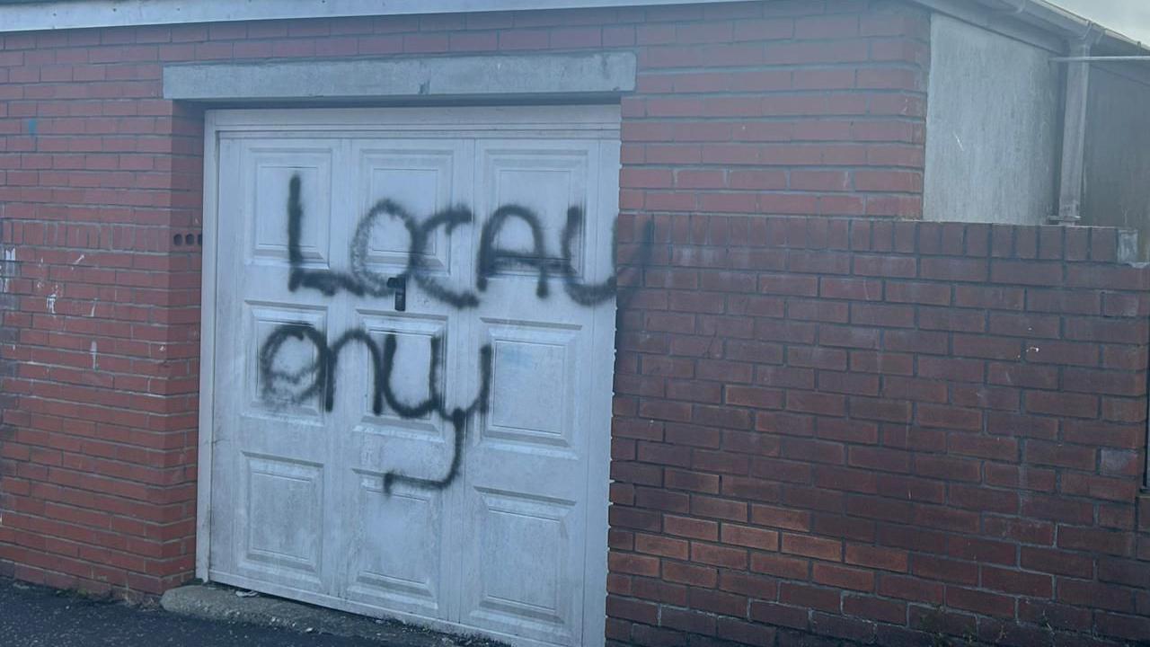 The words "local only" were painted on a white garage door of a red brick house.