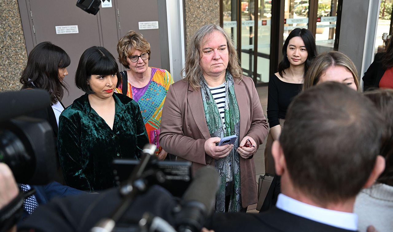 Roxanne Tickle (centre) looks on as she is surrounded by people while speaking to press outside the Federal Court of Australia in Sydney on 23 August.