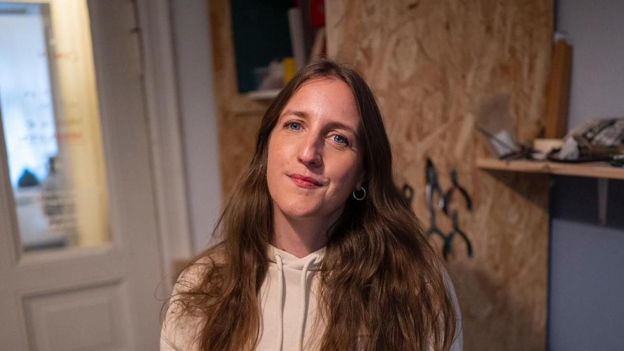 Rebecca smiling while stood in home near door and blue wall.