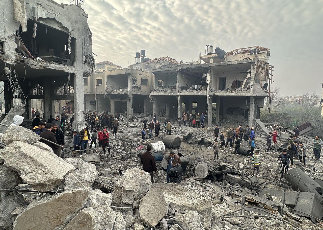 People survey the damage among the rubble of a destroyed building in Jabalia, with extensive damage to buildings in the background, after Israeli strikes overnight, pictured on 16 January