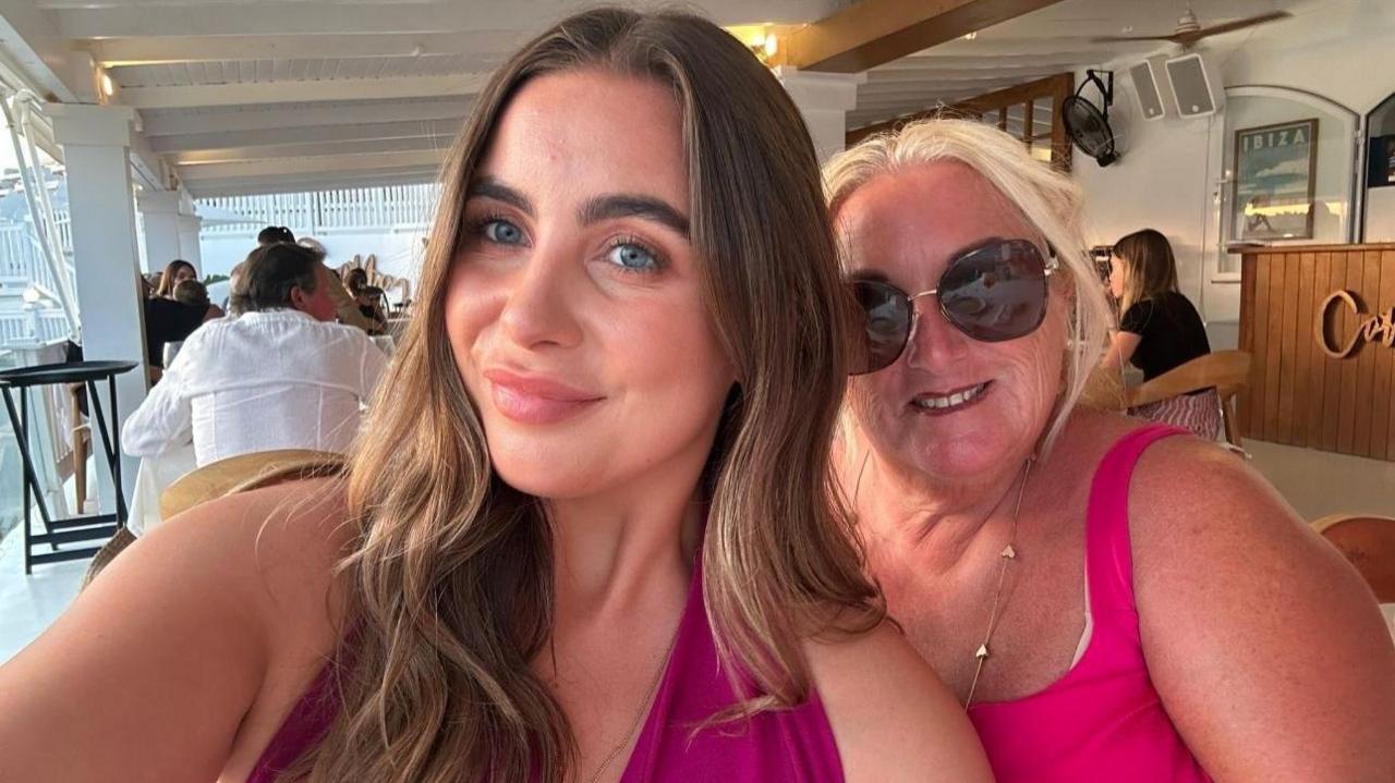 Layla Boudaboussa next to her mother Jeanette who is wearing dark sunglasses. Both are wearing pink vest tops and are in a hotel dining area.