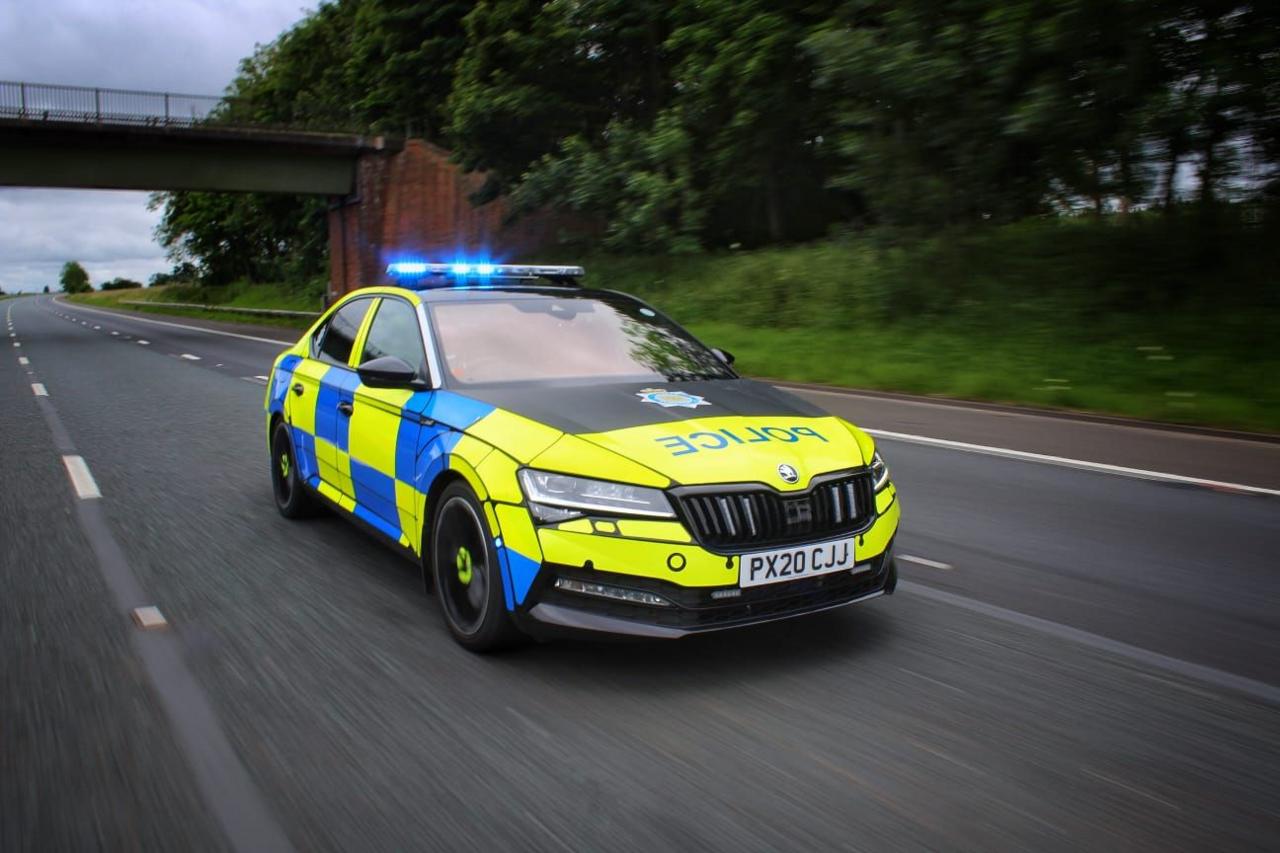 A police car travelling along a motorway with its blue lights flashing. The vehicle has a yellow and blue livery.