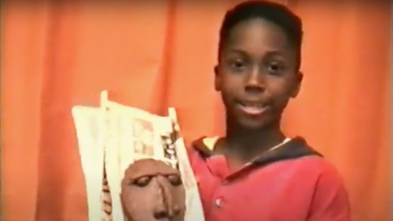 Elijah Turay, as a boy, holds a clay mask.