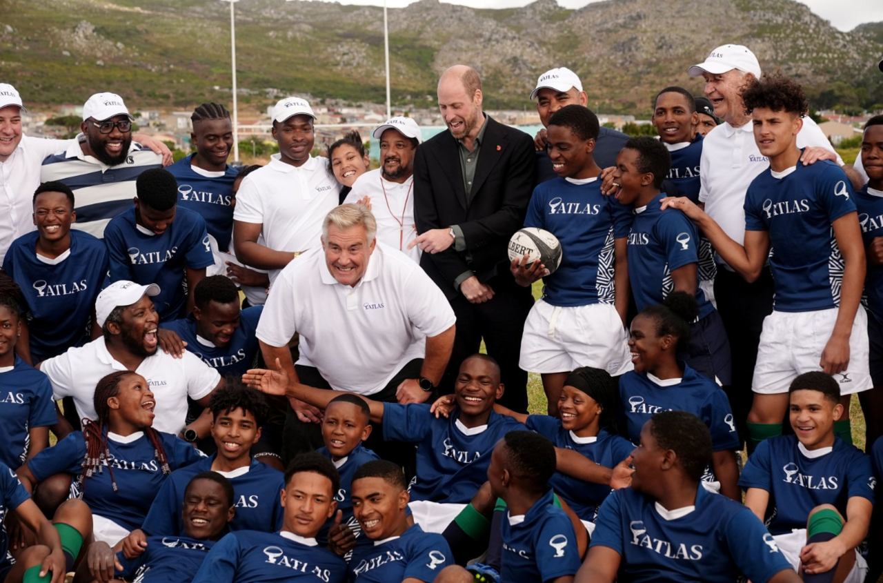 The Prince of Wales poses for a photograph with the local school children after taking part in their rugby coaching session during a visit to Ocean View Secondary School in Cape Town, South Africa.